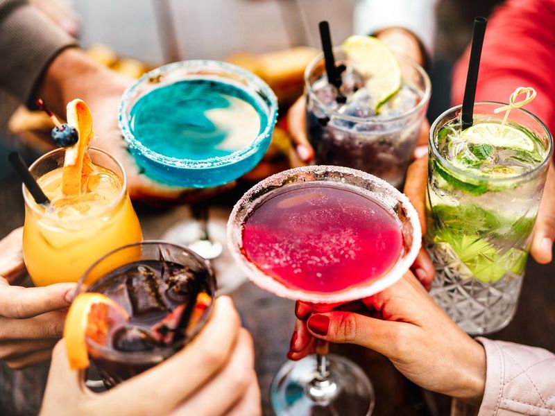 People hands toasting multicolored fancy drinks