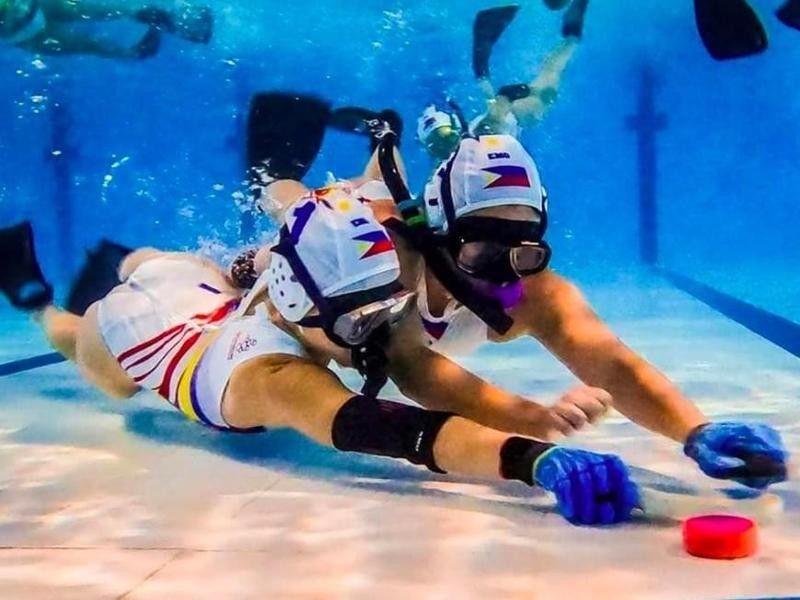 People playing underwater hockey