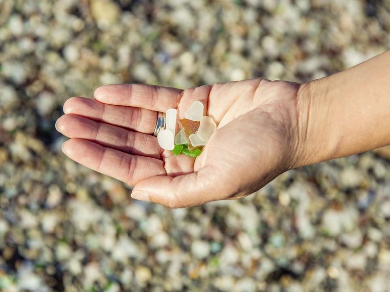 Person holding glass pebbles at Glass Beach in California