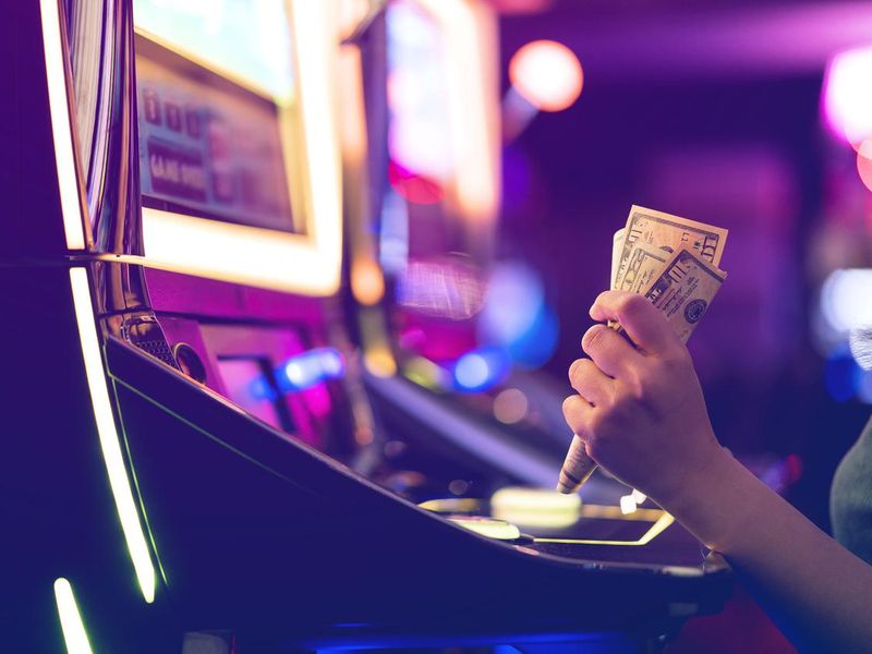 Person holding money at a slot machine