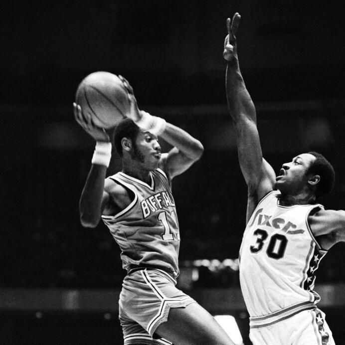 Philadelphia 76ers' George McGinnis, right, tries to stop a shot by Buffalo Braves' Bob McAdoo, left