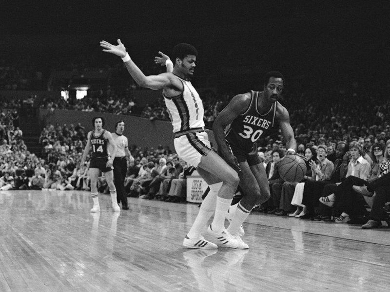 Philadelphia's George McGinnis drives around Trail Blazers' Maurice Lucas as he goes for the basket during their NBA championship