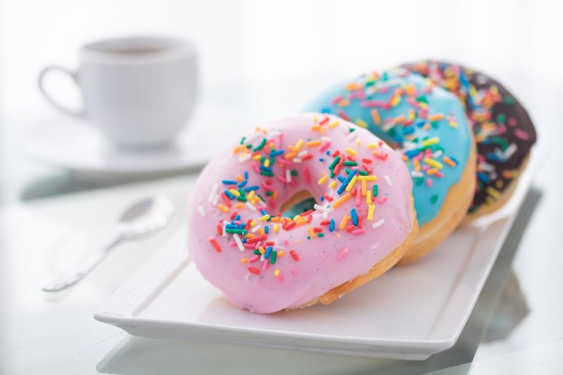 Pink, blue, chocolate sprinkle donuts with a cup of coffee