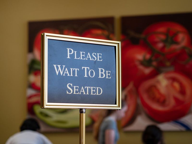 Please wait to be seated sign at the front of a restaurant