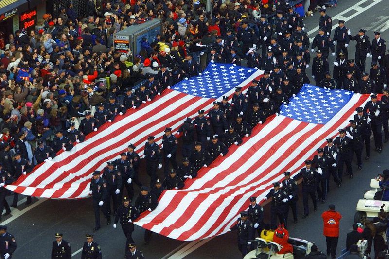 Police and emergency workers hold two 54-foot flag banners in 2001 Thanksgiving Parade in New York