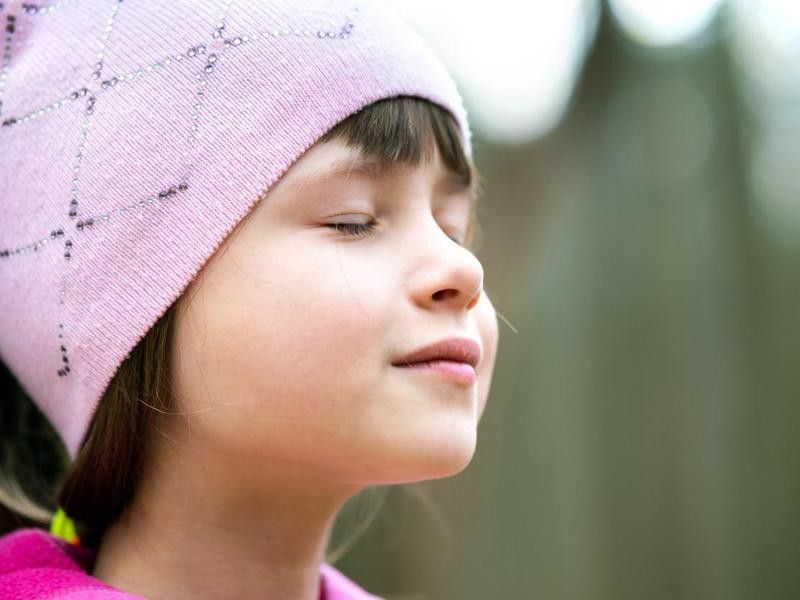 Portrait of young pretty child girl wearing pink jacket and cap enjoying warm sunny day in early spring outdoors.