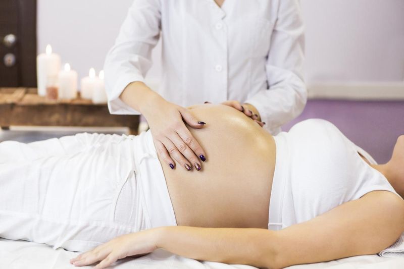 Pregnant woman has massage treatment at spa salon