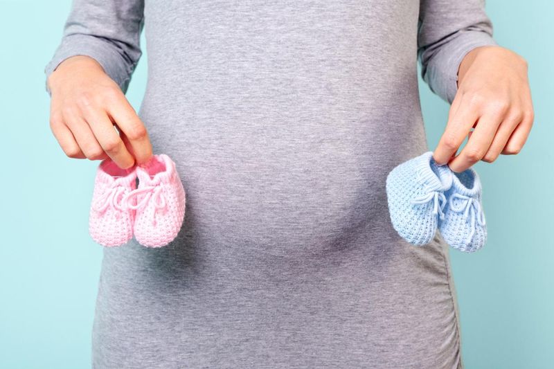 Pregnant woman holding pink and blue baby booties