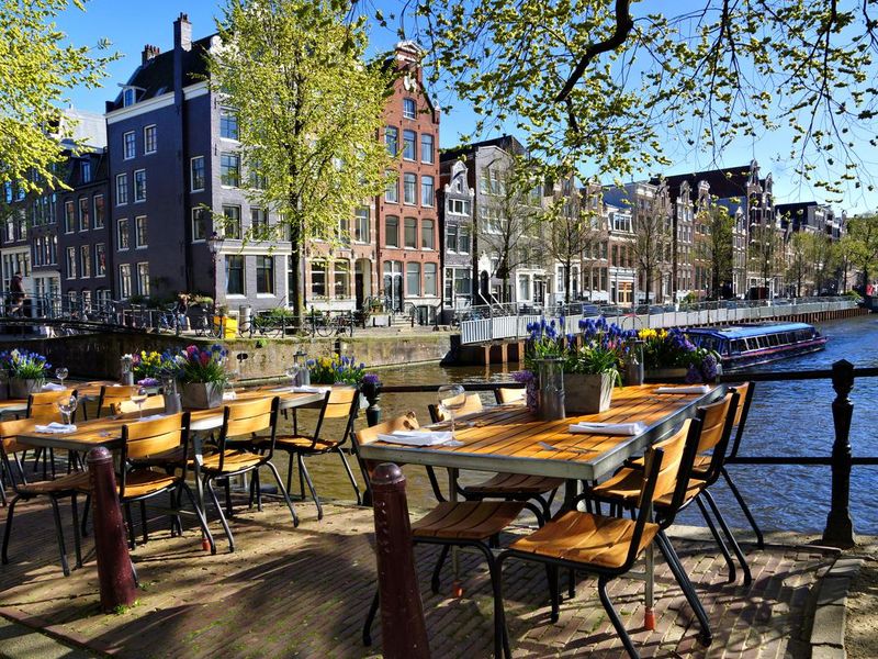 Restaurant tables lining the canals of Amsterdam during springtime, Netherlands
