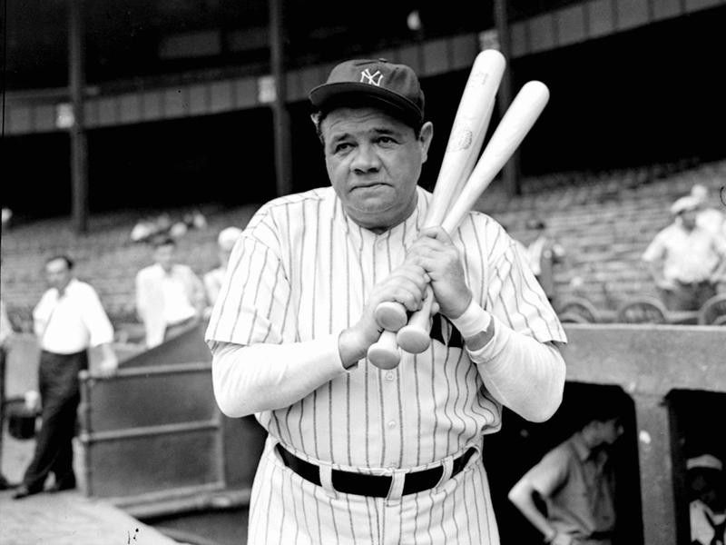 Retired Yankees slugger Babe Ruth warms up with three bats