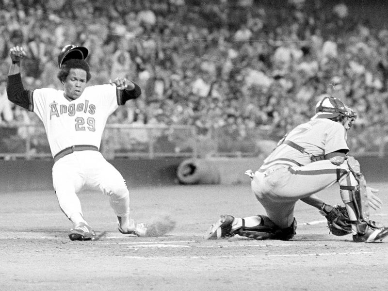 Rod Carew slides into home behind Seattle Mariners