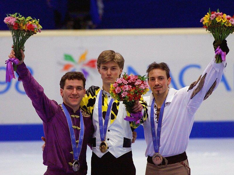 Russia's Ilia Kulik, center, Canada's Elvis Stojko, left, and France's Philippe Candeloro, right, wave to the crowd during the awarding ceremony following the men's free skate competition