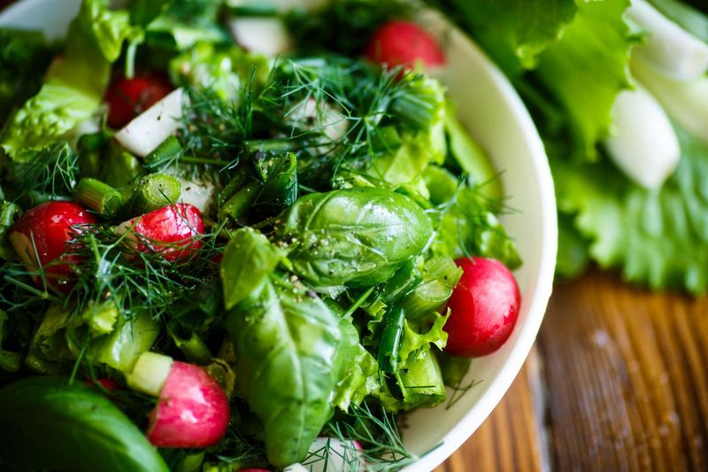 Salad with vegetables, lettuce leaves, radishes and herbs