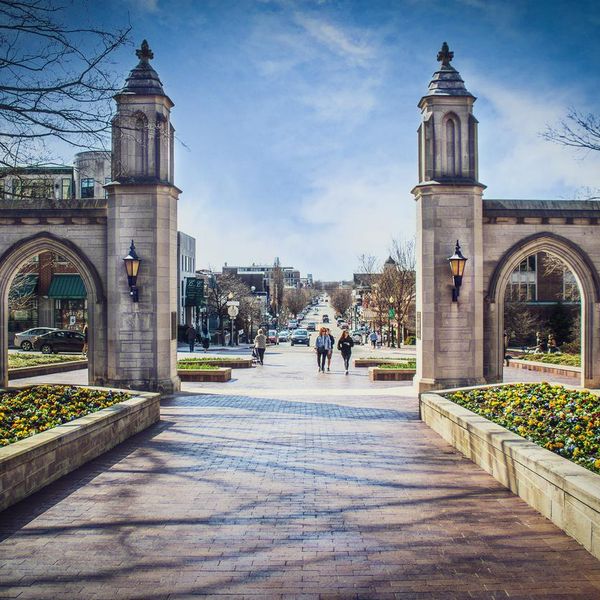03_23_2021 Bloomington USA Sample Gates leading out of Indiana University into downtown with students and a senior lady walking and running and many cars in early spring
