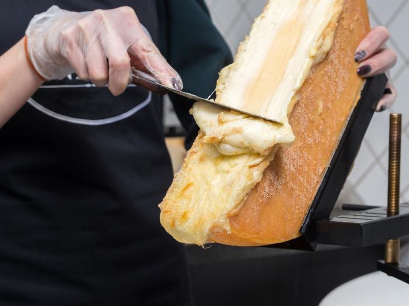 Scraping melted traditional Swiss Raclette cheese