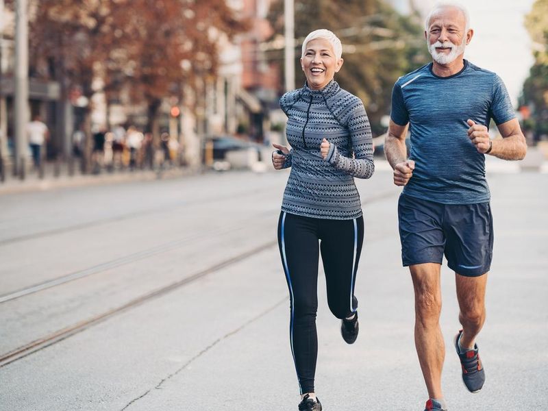 Senior man and senior woman jogging side by side on the street