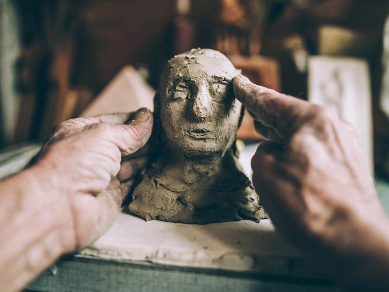 Senior man's hands making statue of clay