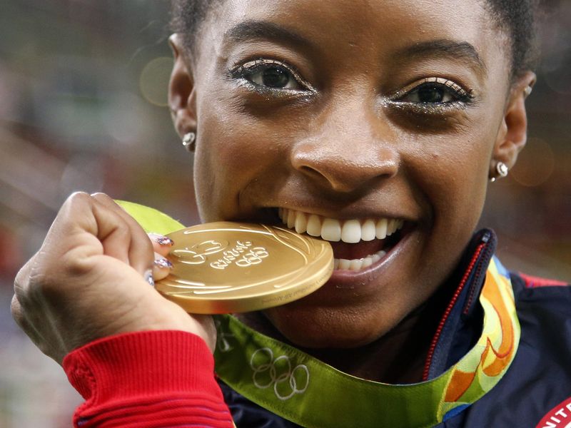 Simone Biles bites her gold medal