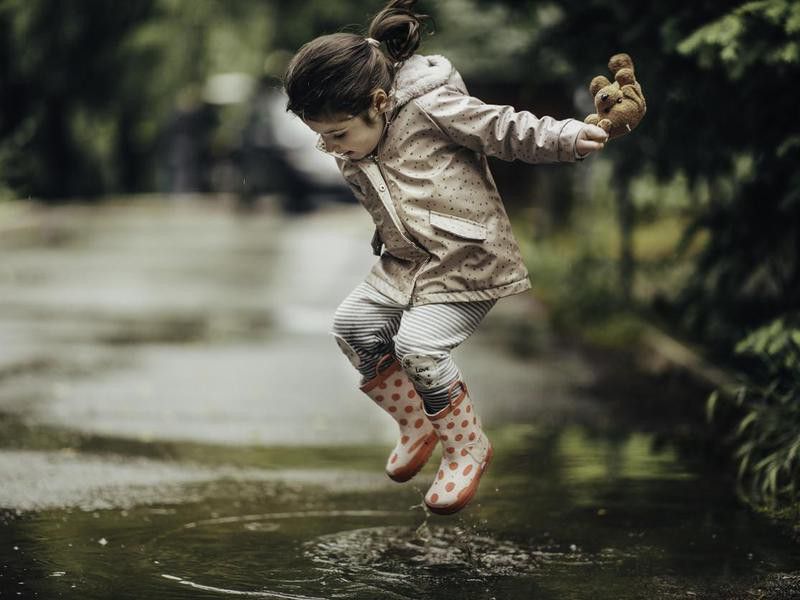 Smiling little girl playing in a puddle