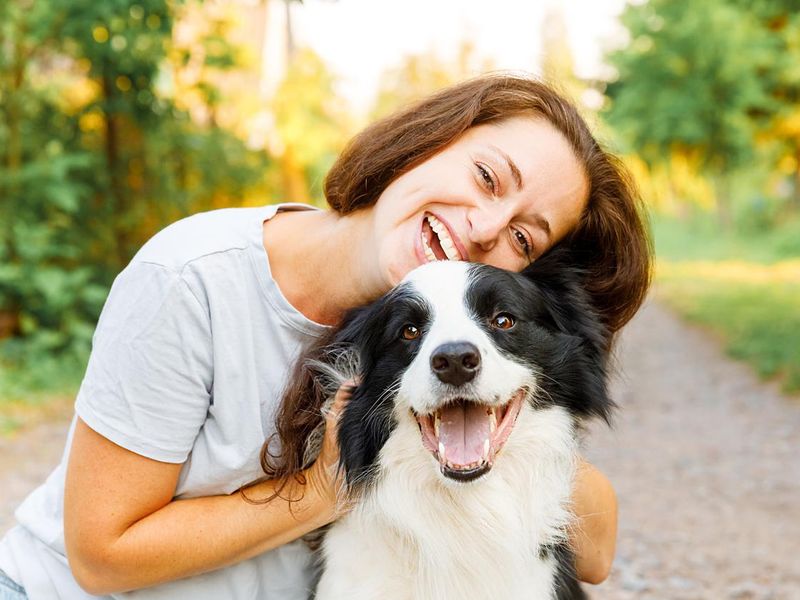 Smiling woman playing with cute puppy dog