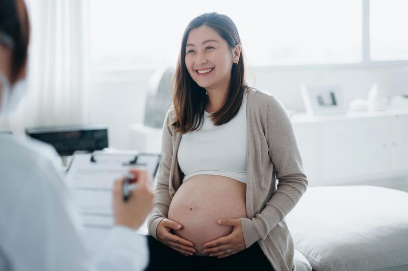 Smiling young Asian pregnant woman having a consultation with a doctor