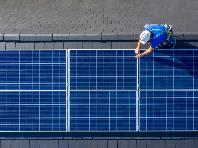 Solar panel installer installing solar panels on roof