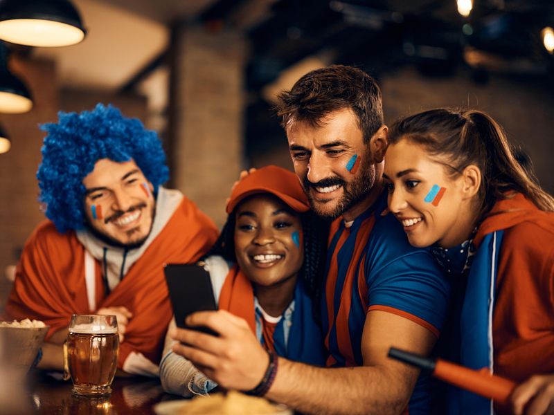 Sports fans mobile sports betting on a soccer game in a bar