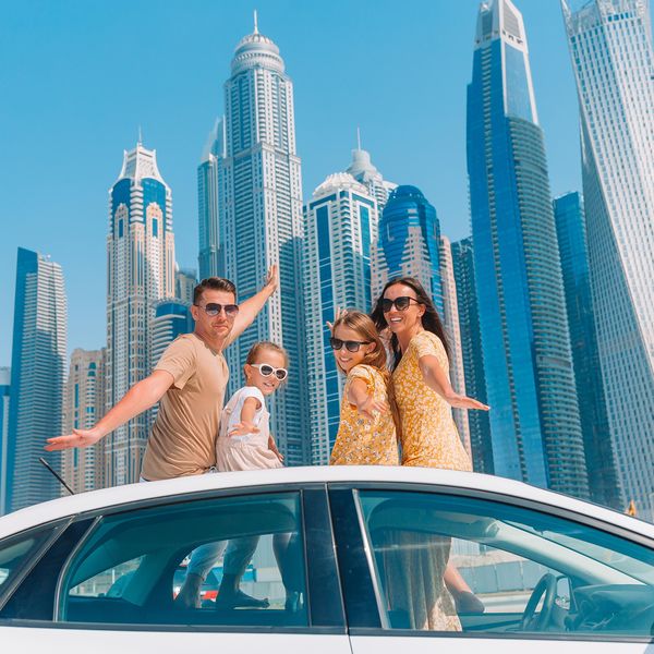 Family summer vacation. Family of four on car vacation on background of skyscrapers in Dubai