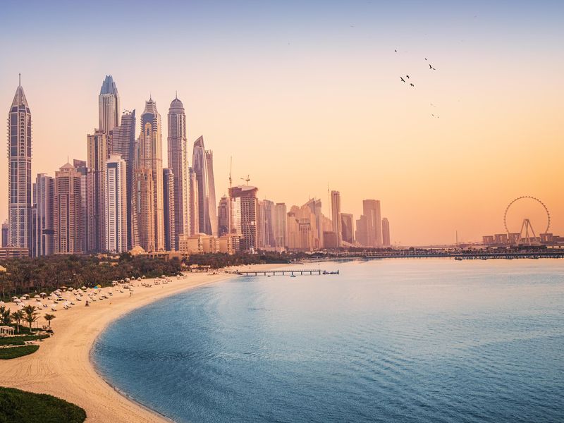 Sunset view of the Dubai Marina and JBR area and the famous Ferris Wheel and golden sand beaches in the Persian Gulf