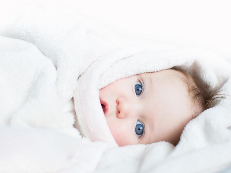 Sweet baby with blue eyes playing peek-a-boo