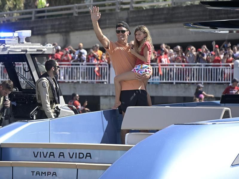 Tampa Bay Buccaneers quarterback Tom Brady holds daughter Vivian Lake while waving to fans