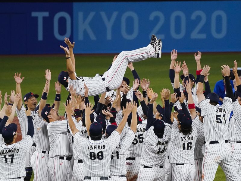 Team Japan toss their manager Atsunori Inaba as they celebrate
