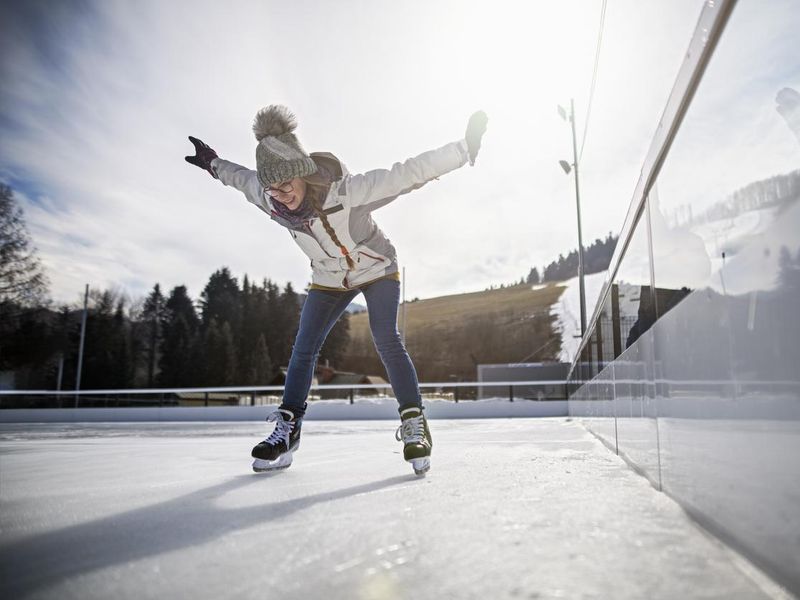 Teenage girl learning to ice skate on outdoors ice rink