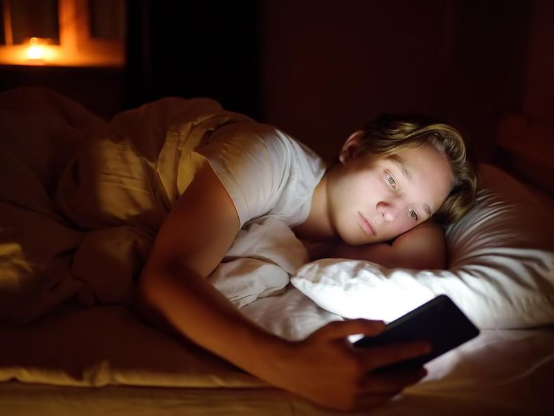 Teenager boy on his. phone in bed