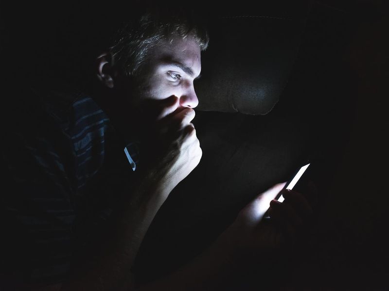 Teenager on his cellphone in the dark