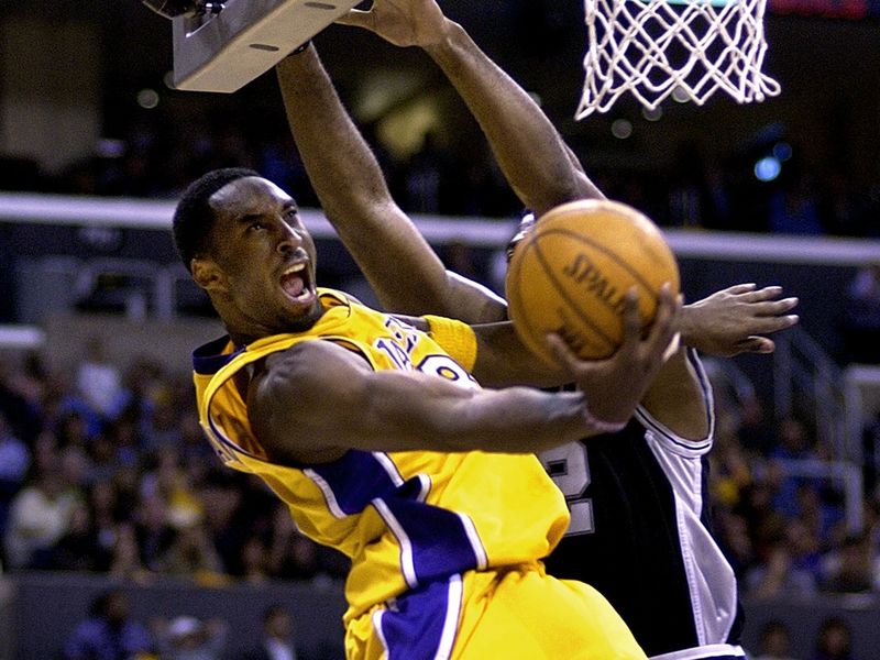 The Los Angeles Lakers' Kobe Bryant swoops under basket and past San Antonio Spurs defender Mark Bryant to score