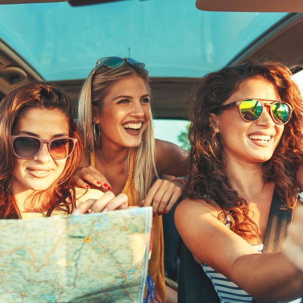 Three female friends enjoying traveling at vacation in the car.
