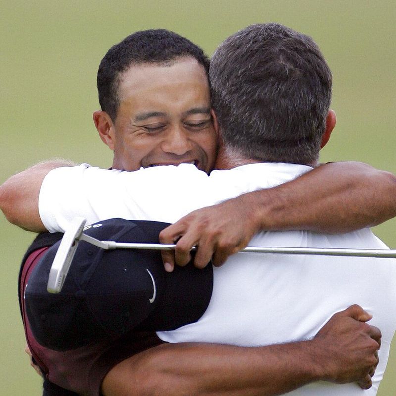Tiger woods hugging caddie with putter golf club