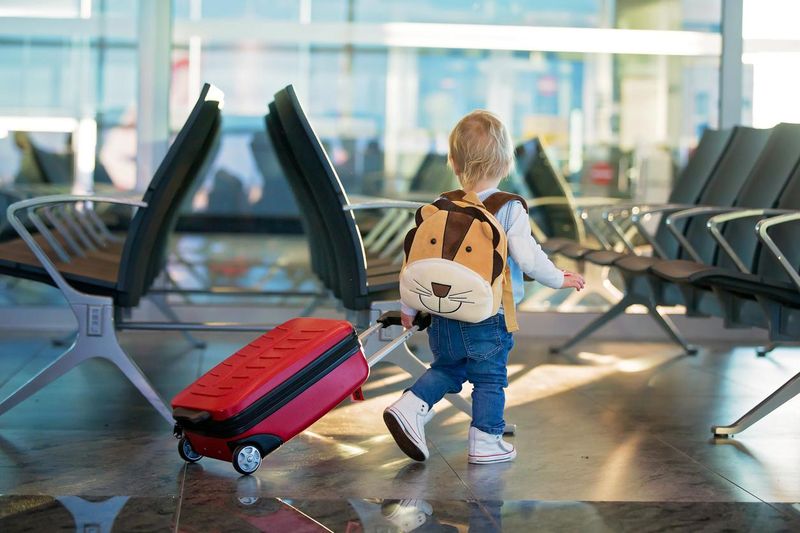 Toddler in the airport pulling a suitcase