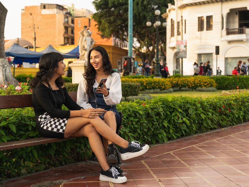 Two friends talking while using the mobile in the street