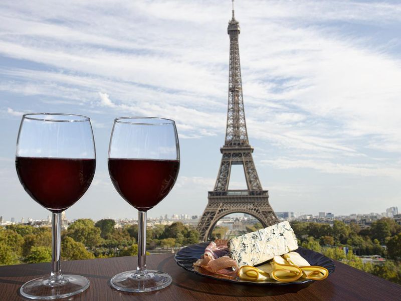 Two glasses of red wine with charcuterie assortment on view of Paris and Eiffel tower background