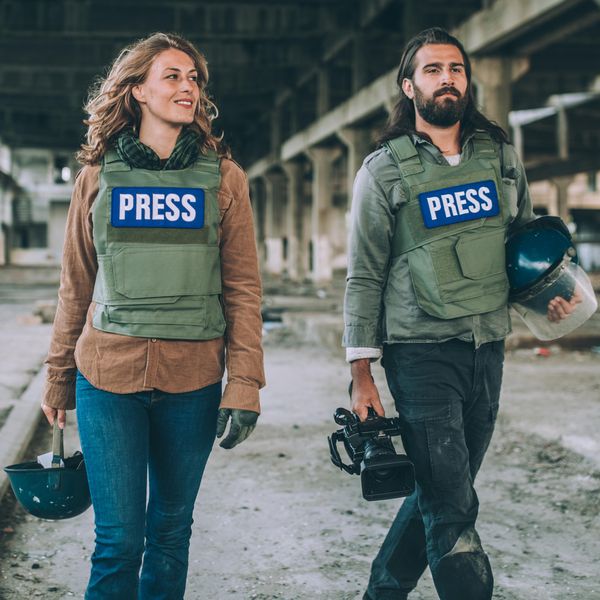 Two young journalists, man and woman in the war zone