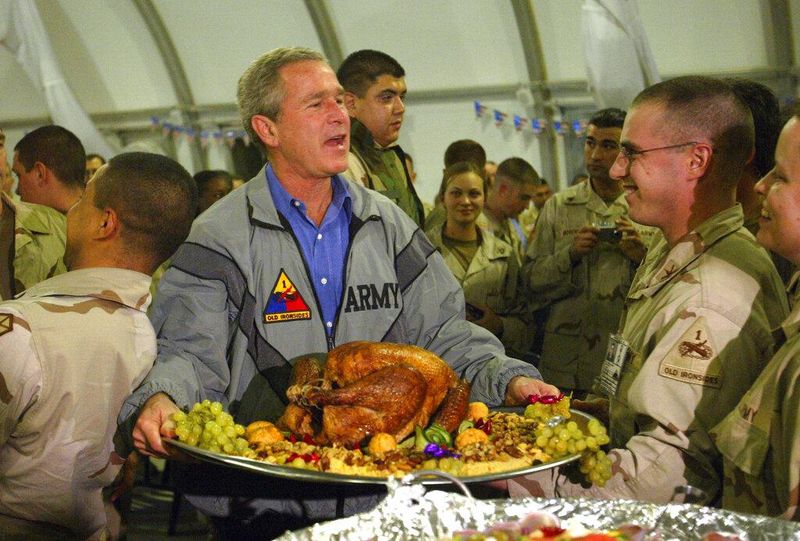 U.S. President George W. Bush carries a turkey platter while visiting U.S. troops for 2003 Thanksgiving in Baghdad