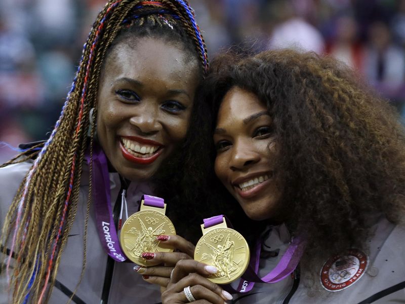 Venus Williams and Serena Williams showing gold medals in women's doubles
