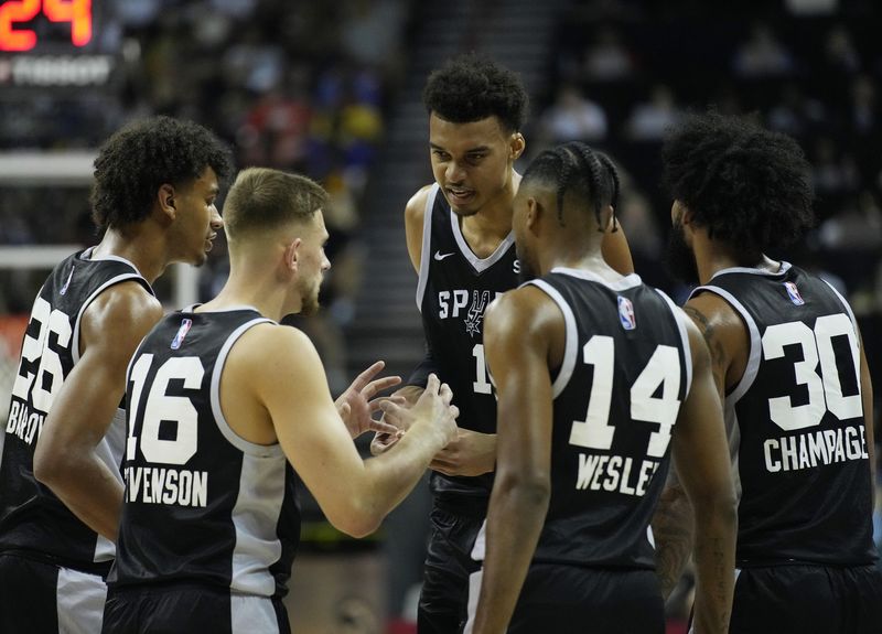 Victor Wembanyama, center, speaks with Spurs teammates during NBA summer league game