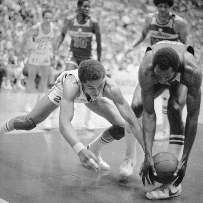 Washington Bullets Elvin Hayes reaches in to grab loose ball from Seattle Supersonic Dennis Johnson