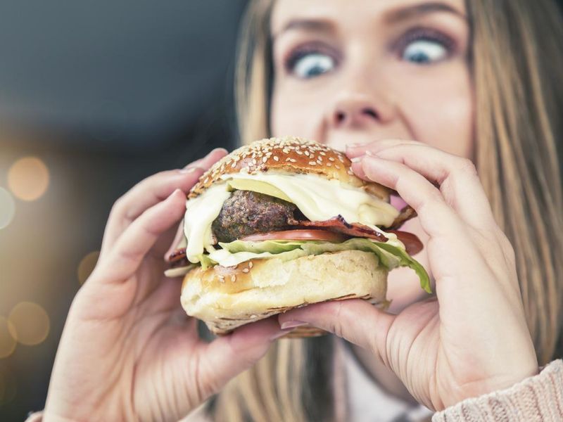 Wide-eyed girl looks down at enormous burger