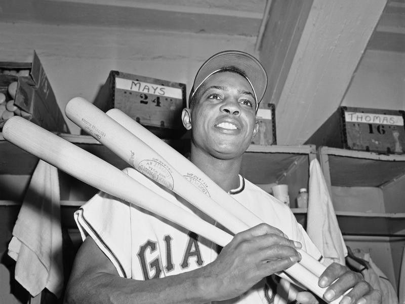 Willie Mays holding bats in the clubhouse