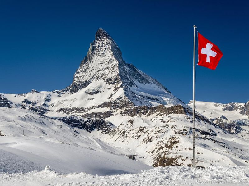 Winter view of Matterhorn with a weaving Swiss flag, Zermatt, Valais, Switzerland
