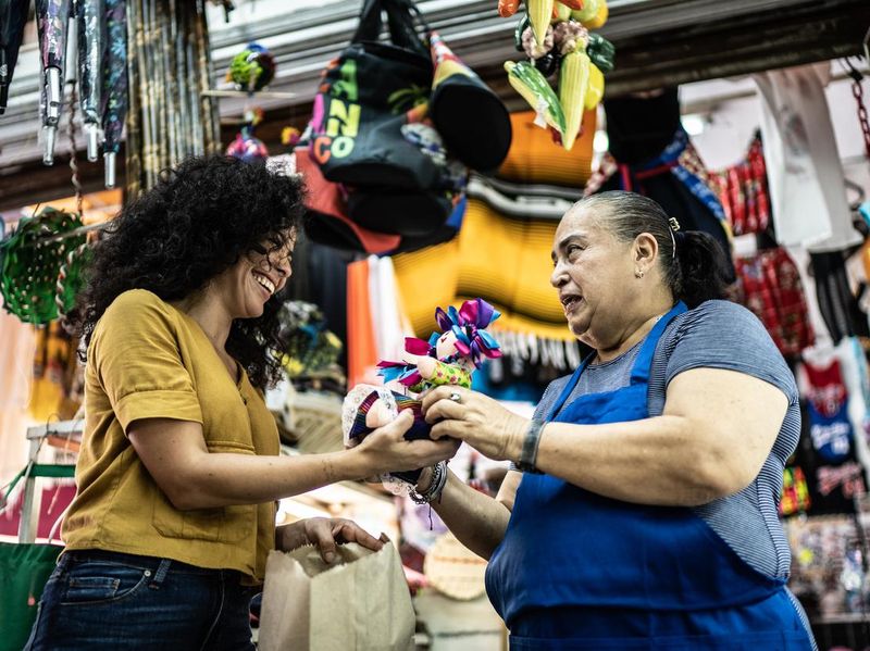 Woman buying Mexican doll from saleswoman at a gift shop